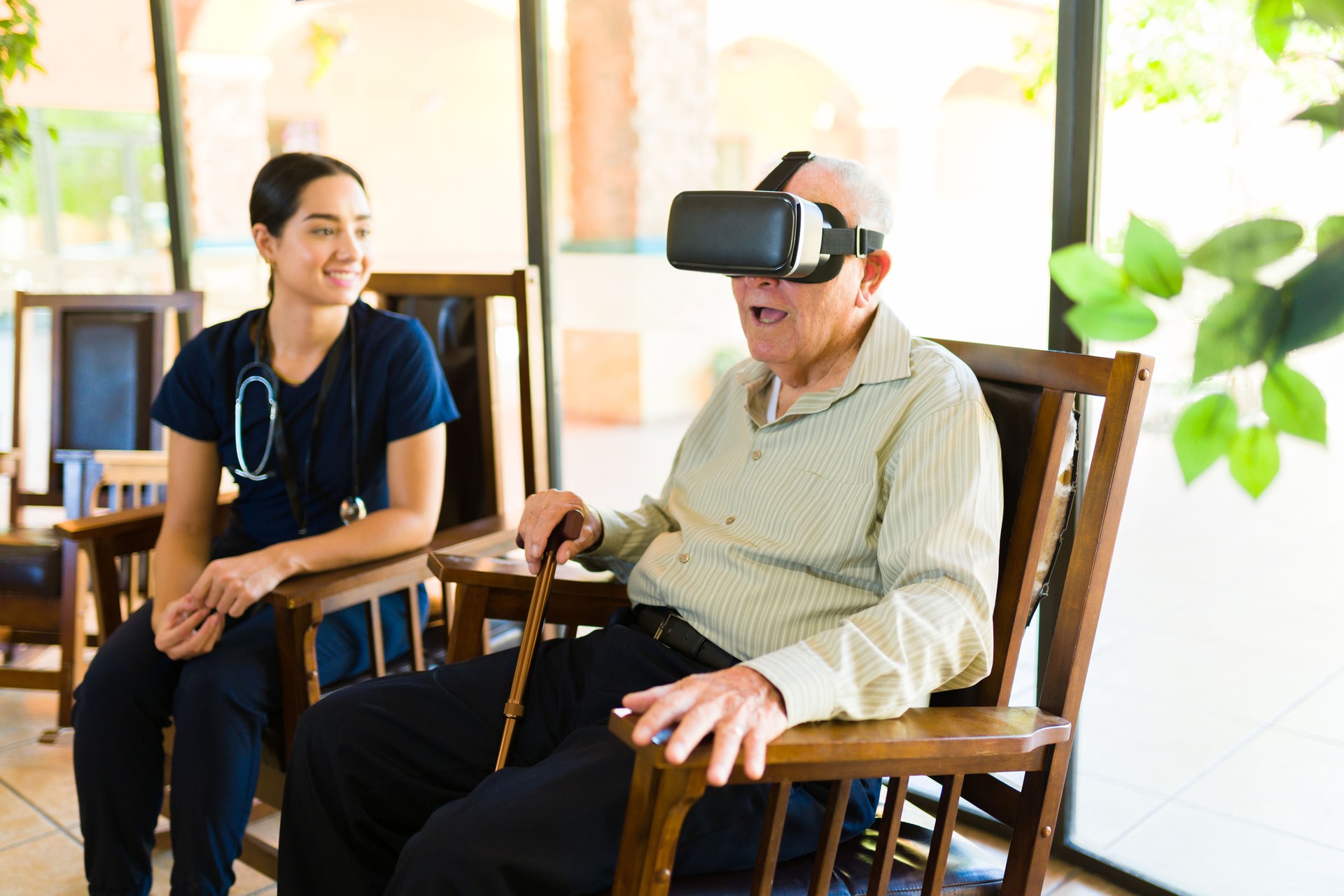 Happy elderly man playing with virtual reality glasses at the retirement home